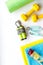 Fitness background - dumbbells, jump rope, sport carpet, water bottle - on white top-down copy space