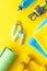 Fitness background - dumbbells, jump rope, sport carpet, water bottle - on yellow top-down
