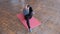 Fitness body flex. The athletic girl in a gray T-shirt and black tights lies on a pink rug and alternately bends her