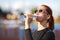 Fitness Caucasian Woman in Sportwear and Sunglasses Drinking Water from Bottle Outdoors