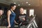 Fitness coach helps woman on elliptical trainer