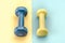 Fitness concept with dumbbells/blue dumbbell on a yellow background yellow on blue. Close up. Top view