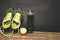 Fitness concept photo. Trainers, bottle of water and fruit apple are standing on wooden background. Healthy lifestyle. Sport