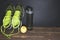 Fitness concept photo. Trainers, bottle of water and fruit apple are standing on wooden background. Healthy lifestyle. Sport