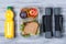 Fitness concept, sandwich and fruits to go, orange juice and dumbbells, wooden background, top view