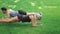 Fitness couple man and woman training plank exercise on grass in summer park