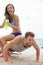 Fitness couple training together having fun. Happy girl laughing sitting on top of personal trainer to make the workout