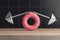 Fitness and Diet Concept. Curved Barbell or Dumbbells for Weightlifting over Big Strawberry Pink Glazed Donut. 3d Rendering