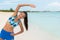 Fitness exercise woman stretching during yoga or pilates class on beach. Happy Asian girl exercising outdoors wearing sports bra