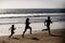 Fitness family running on a sandy beach. Sporty family father, mother and baby son running together. Child with parents
