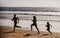 Fitness family running on a sandy beach. Sporty family father, mother and baby son running together. Child with parents