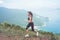 Fitness female athlete wearing black sportswear doing cardio exercise, running in mountains with inspirational sea view