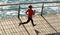 Fitness female runner running on seaside boardwalk