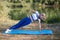 Fitness girl on the river bank on the rug