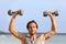 Fitness gym man lifting dumbbell weights. Male athlete with muscular arms with dumbbells overhead doing shoulder press training