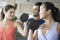 Fitness instructor helping two young women lift weights in the gym