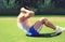 Fitness man doing abdominal exercises outdoors on the grass