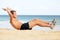 Fitness man doing crunches sit-ups on beach