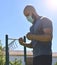 Fitness man doing wrist stretch in a public park and wearing a face mask