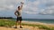Fitness man exercising on beach doing Squat with Overhead Dumbbell Swing