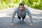 Fitness man exercising push ups, outdoor. Muscular male cross-training on city park