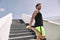Fitness man runner getting ready to run stretching legs warm up quad stretch exercise on outdoor staircase cardio HIIT