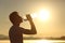 Fitness man silhouette drinking water from a bottle