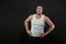 Fitness man stand with hands on hips. Macho in trendy vest and hat on dark background. Sportsman with confidence and