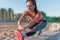 Fitness model athlete girl warm up stretching her hamstrings, leg and back. Young woman exercising with headphones