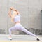 Fitness model woman in a beautiful slim sporty body in fashionable sportswear with white jogging sneakers does stretching near a