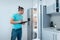 fitness nutritionist man with clipboard revising or look at fridge at kitchen