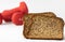 Fitness protein bread and unfocused red dumbbells on background.