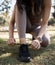 Fitness, running and woman tie shoes in grass of park for training, workout and ready. Exercise, health and wellness