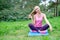 Fitness, sport, training, park and lifestyle concept - smiling woman doing exercises on mat outdoors
