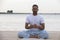 Fitness, sport, yoga and healthy lifestyle concept - close up of people meditating in easy sitting pose on river or lake berth