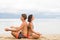 fitness, sport, yoga, people and lifestyle concept - happy couple sitting in lotus pose on beach