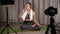 fitness, sports and vlogging concept - woman or blogger with camera on tripod recording online yoga lesson. He takes a