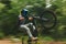 Fitness, trail and man doing a trick on a bike while riding for competition practice in the woods. Extreme sports, blur