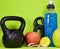 Fitness training accessories, an apple and an energetic drink on a green background