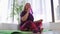 Fitness training - blonde overweight woman sitting on yoga mat and drinks water from a bottle