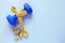 Fitness and weight loss concept. Blue dumbbell with bow of yellow centimeter on a blue background. Top view.