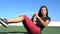 Fitness woman doing ab exercise workout on grass doing Russian Twists