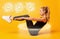 Fitness woman doing abs exercise with legs and hands raised over. Yellow background.