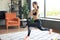 Fitness woman doing forward lunge exercises and watching online tutorials on laptop, training in living room