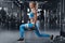 Fitness woman doing lunges exercises for leg muscle workout training in gym. Active girl doing front forward one leg step