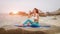 Fitness woman drink water after doing sport exercises on beach at sunset.