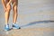 Fitness woman jogger hold her sports injured leg at seaside