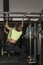 Fitness woman pumps abs on horizontal bar in gym. Girl with sports figure does full-body workout