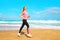 Fitness woman is running summer along the beach near the sea