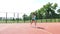 Fitness woman in sportswear doing various exercises on an orange basketball field with white markings, at the stadium